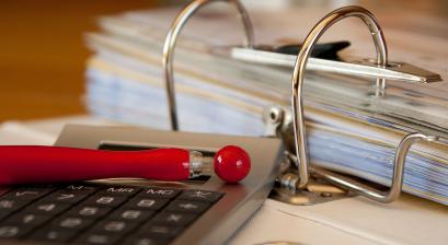 Segregator z dokumentami, długopis i kalkulator 