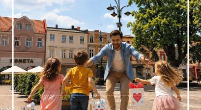 zdjęcie mężczyzny, w kierunku którego biegną małe dzieci z torebkami prezentowymi na Rynku miejskim w Lublińcu 