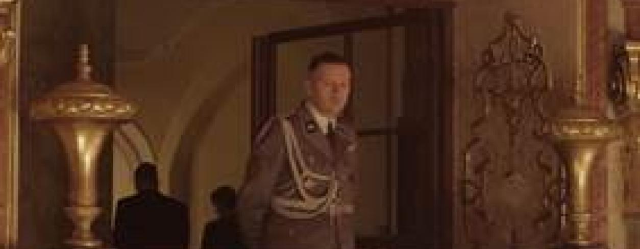 Plakat filmu STREFA INTERESÓW. Mężczyzna w niemieckim mundurze stojący na balkonie w pałacu