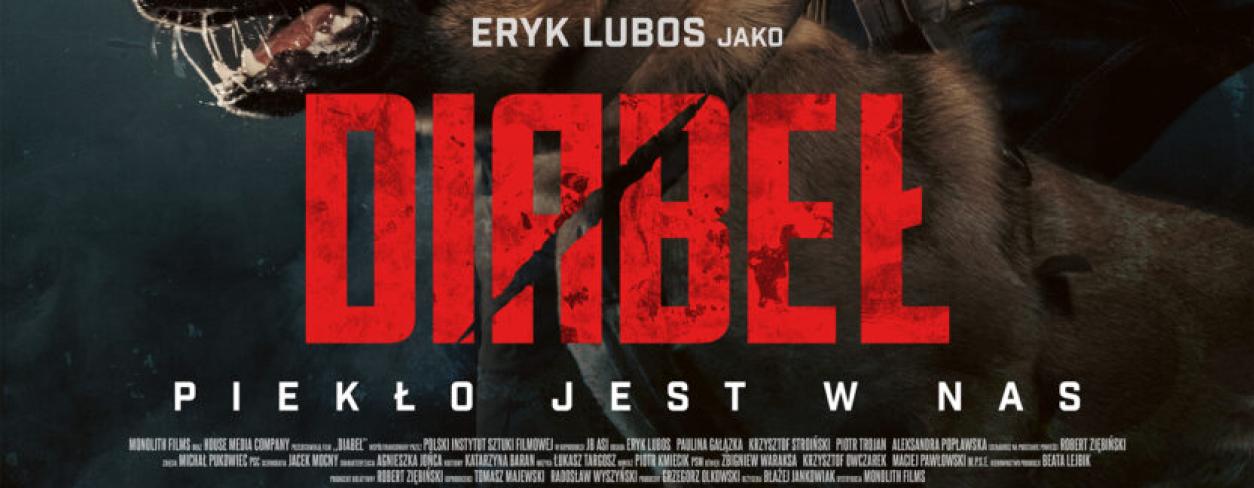 główni bohaterowie filmu zwróceni w lewą stronę, mężczyzna trzyma owczarka niemieckiego, który warczy 