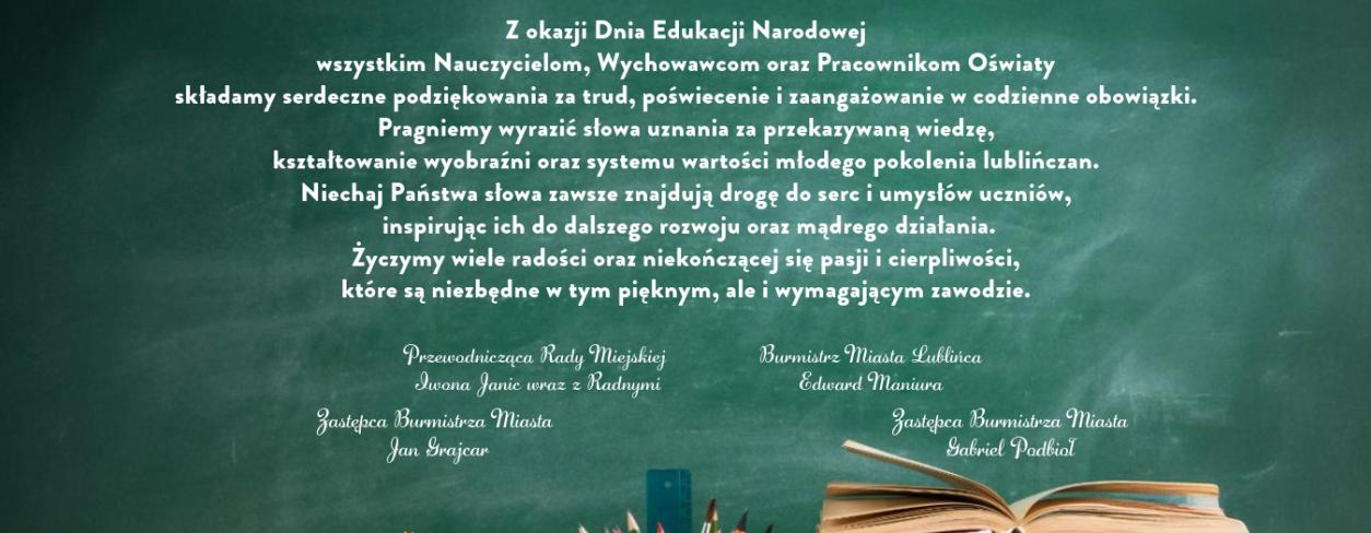 Życzenia dla nauczycieli na pisane białą kredą na zielonej tablicy za biurkiem, na którym leżą książki oraz bukiet kwiatów