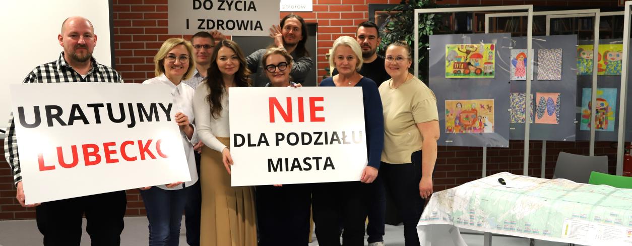 Radni rady miejskie, przedstawiciele Urzędu Miejskiego oraz mieszkańcy trzymają transparenty z hasłami przeciw budowie trasy S11 w wariancie D