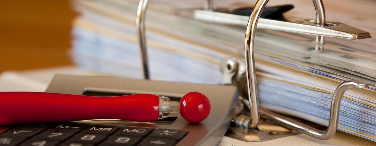 Segregator z dokumentami, długopis i kalkulator 