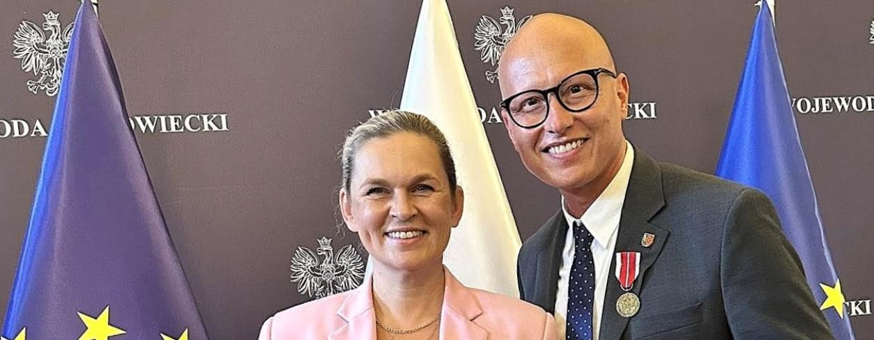 Minister edukacji Barbara Nowacka oraz zastępca burmistrza Gabriel Podbioł na tle flag 