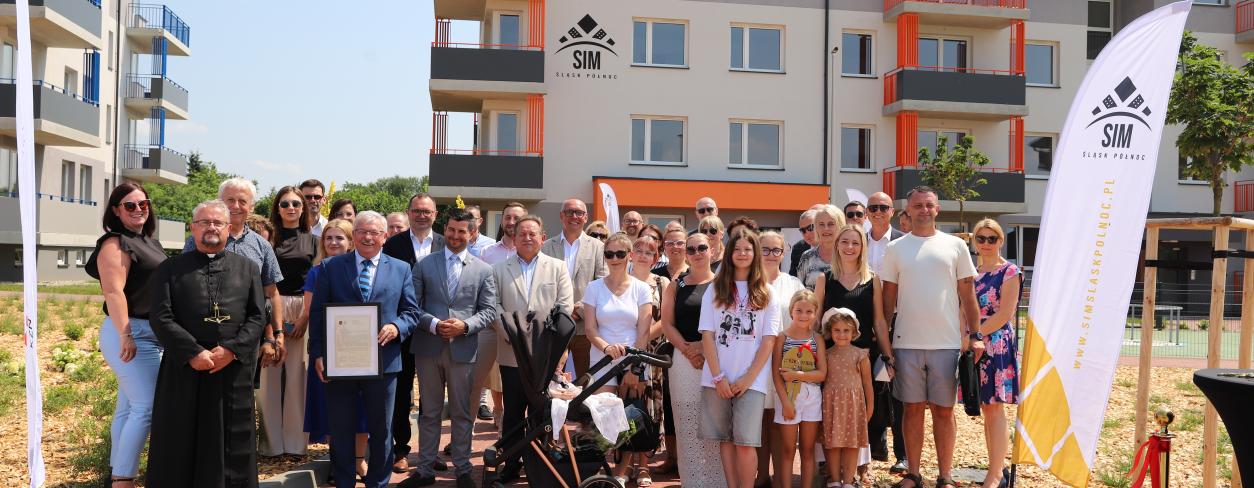 Goście uroczystości na tle bloku 