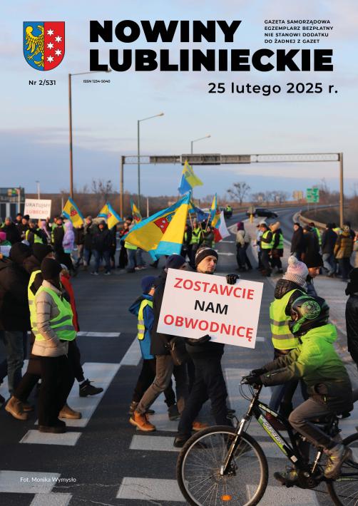 grupa protestujących przechodzących na przejściu przez DK46 na pierwszym planie jeden z protestujących z hasłem protestu "zostawcie nam obwodnice" 