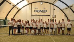drużyna z Lublińca stoi na polu tenisowym za siatką z nagrodami za zwyciestwa w poszczególnych kategoriach 